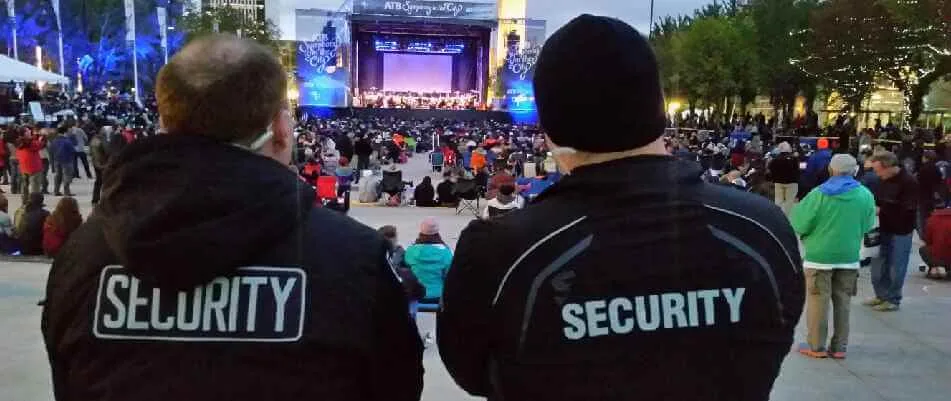 Two security guards standing in front of an event venue, ensuring safety at a public show.