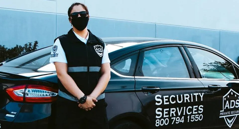 Professional woman in security uniform beside vehicle, illustrating a security guard career.