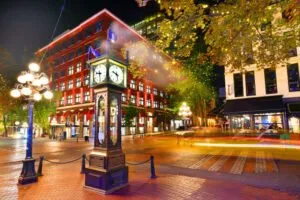 Gastown's iconic steam clock at night, surrounded by vibrant lights and historic buildings.