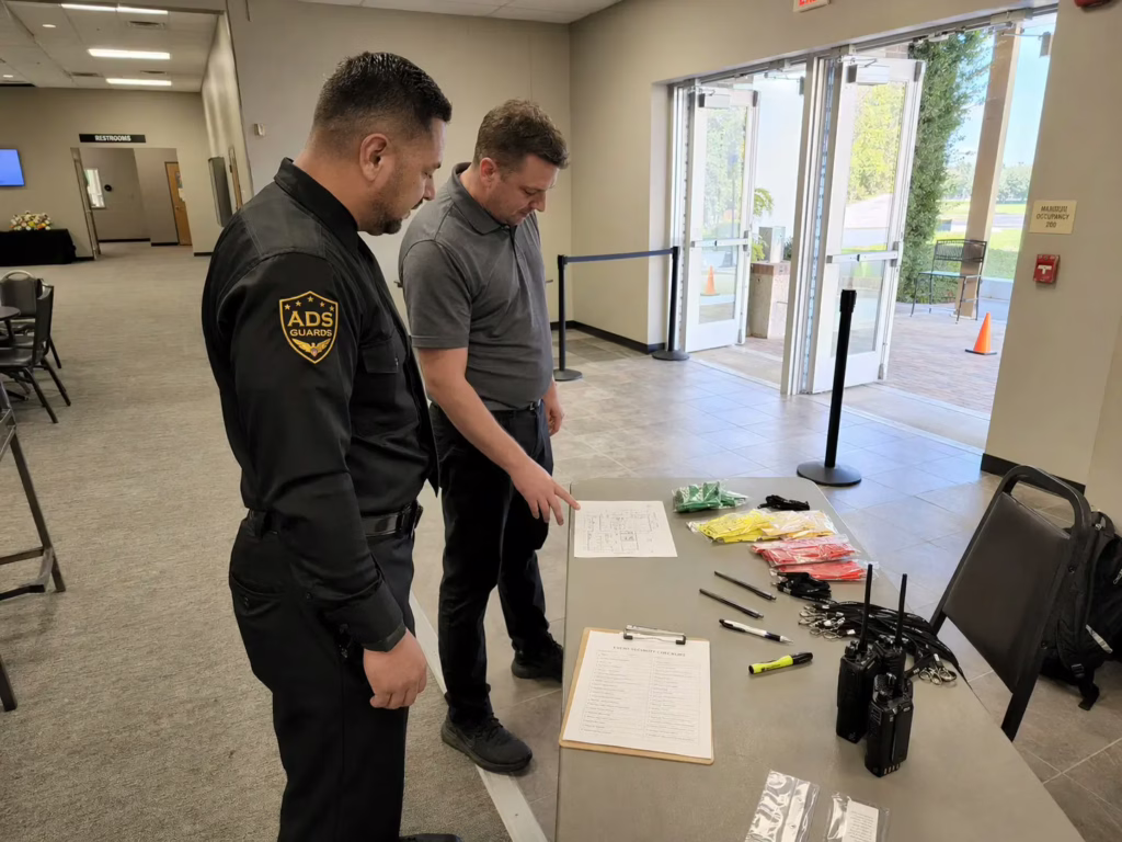ADS Guards security guard and event staff member reviewing an event security checklist at a registration table inside a venue before guests arrive.